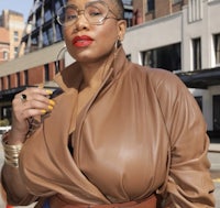 a woman in a tan leather jacket posing on the street